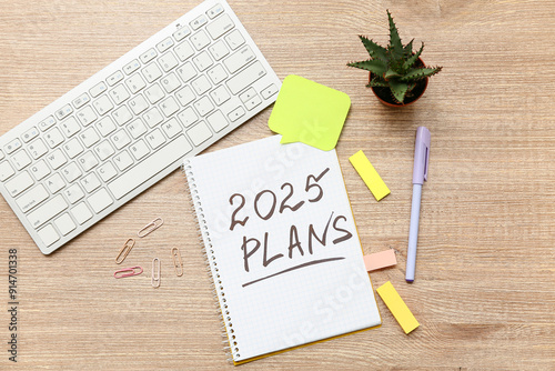 Notebook empty with to do list, computer keyboard and sticky notes on wooden background. New year goals concept