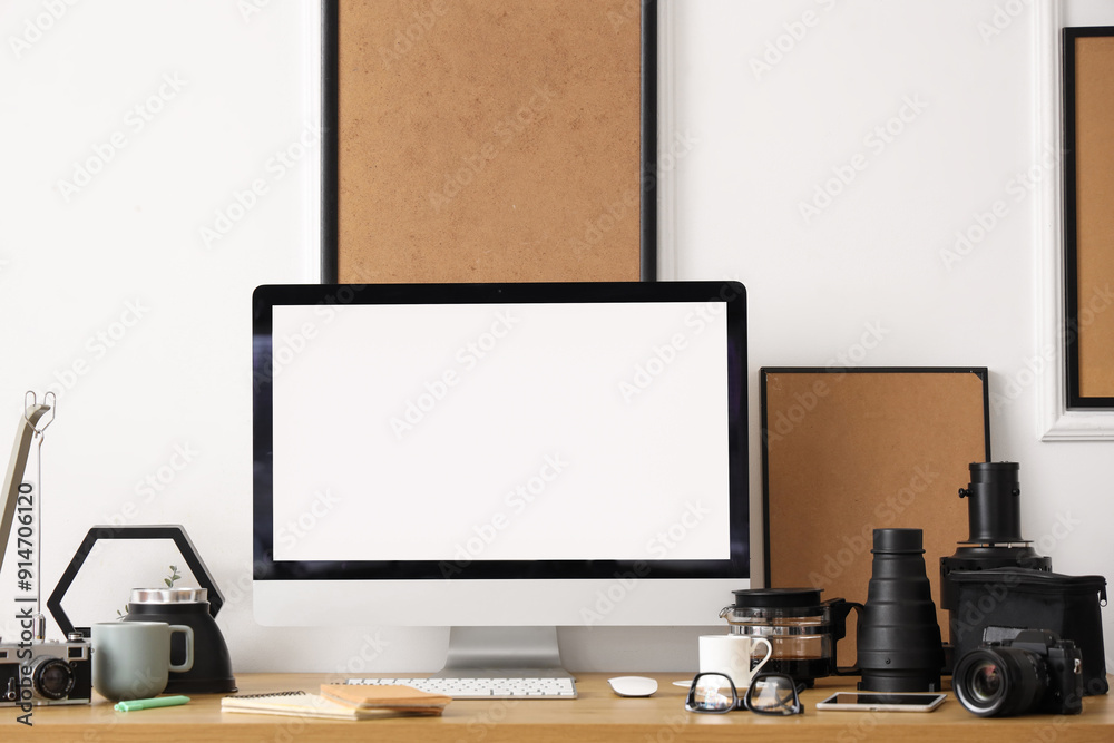 Stylish workplace with modern computer and photo camera near white wall in light office Stylish workplace with modern computer and photo camera near white wall in light office