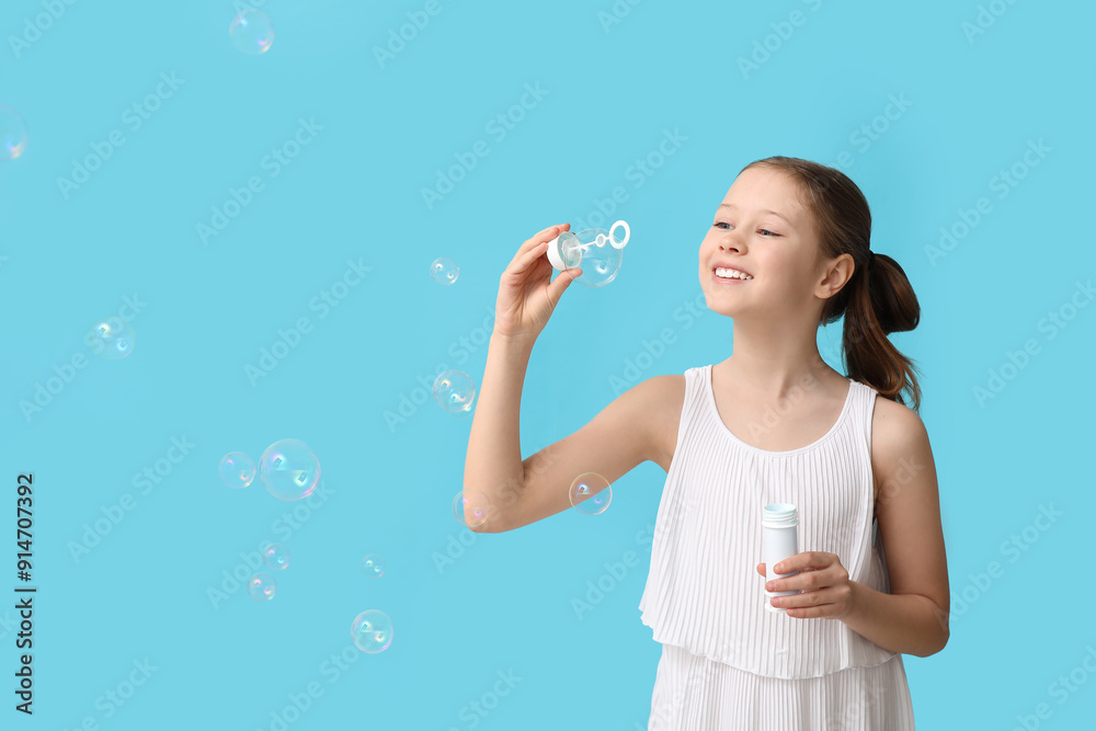 Cute girl blowing soap bubbles on blue background Cute girl blowing soap bubbles on blue background