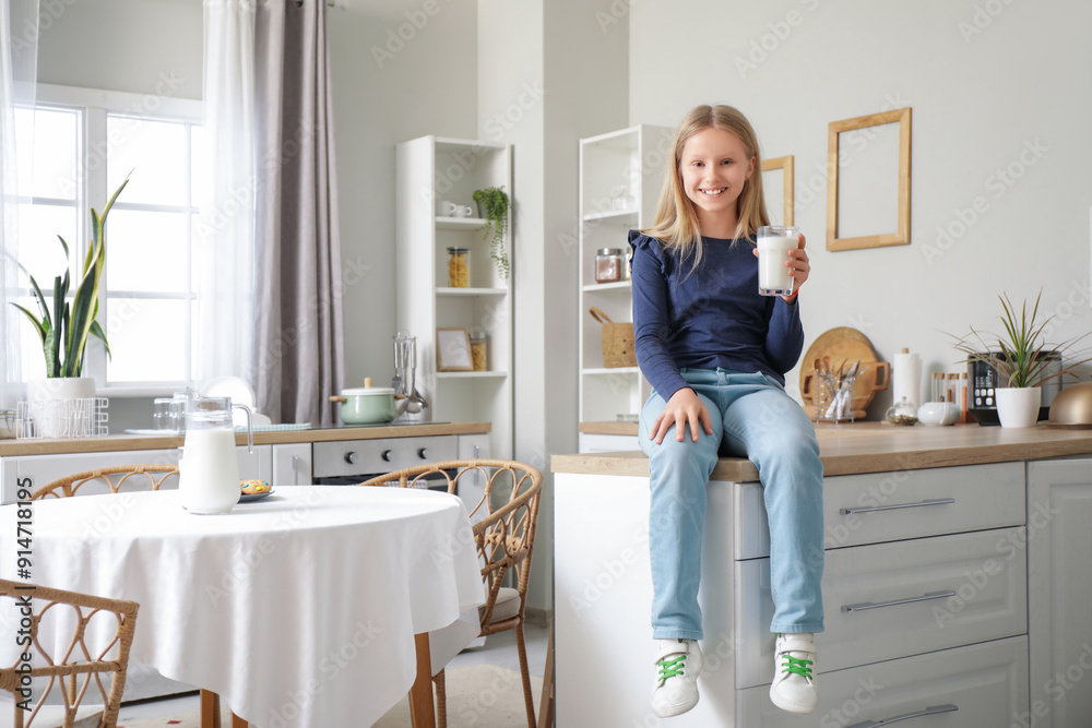 Little girl with glass of milk sitting on counter in kitchen Little girl with glass of milk sitting on counter in kitchen