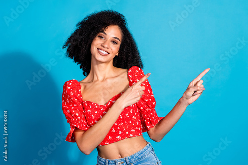 Photo of pretty young woman indicate fingers empty space wear top isolated on blue color background