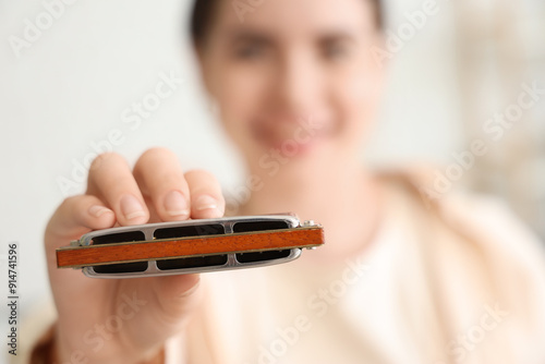 Young woman with harmonica at home, closeup photo