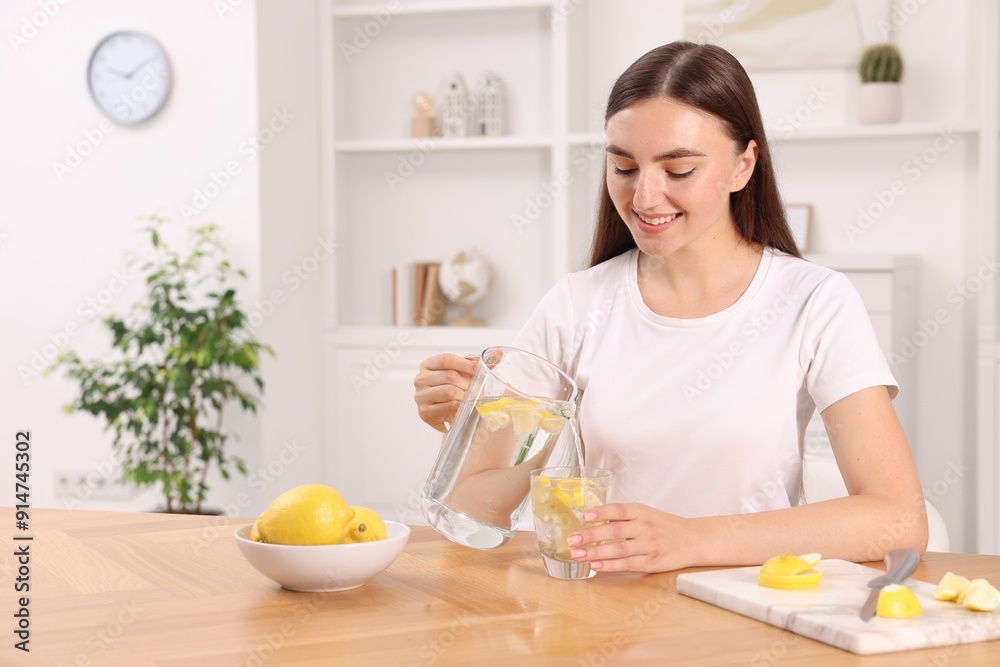 Woman pouring lemon water from jug into glass indoors. Space for text Woman pouring lemon water from jug into glass indoors. Space for text