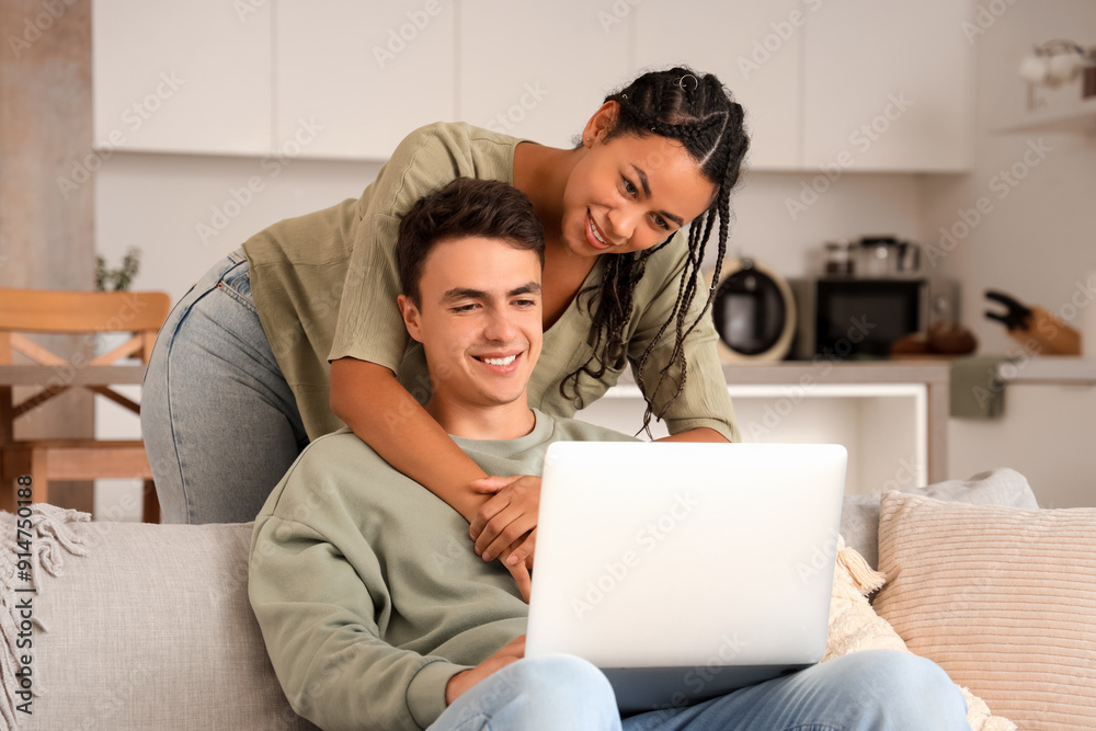 Young couple using laptop on sofa at home