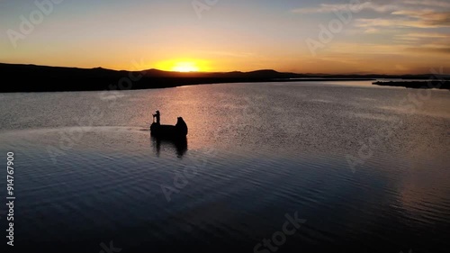 Typical man from Puno Peru sailing on Titicaca Lake with traditional boat at sunset