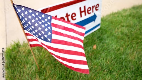 vote here sign with American flag waving rack focus from flag to sign to flag