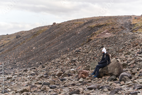 Young woman sitting on a rock enjoying the mountain view