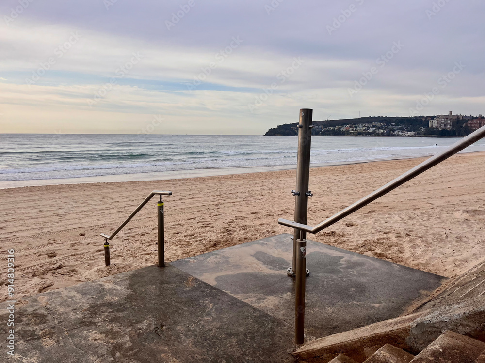 A beach shower and stone stairwell overlooking the ocean on a cloudy day in Australia A beach shower and stone stairwell overlooking the ocean on a cloudy day in Australia