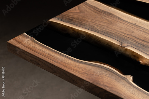 Expensive vintage furniture. The table is covered with epoxy resin and varnished. Luxury quality wood processing. Wooden table on a dark background. Black river made of epoxy resin. photo