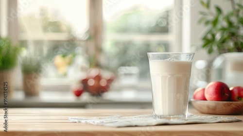 Apple juice carton pouring into glass, cozy kitchen with wooden elements, red apples on counter.