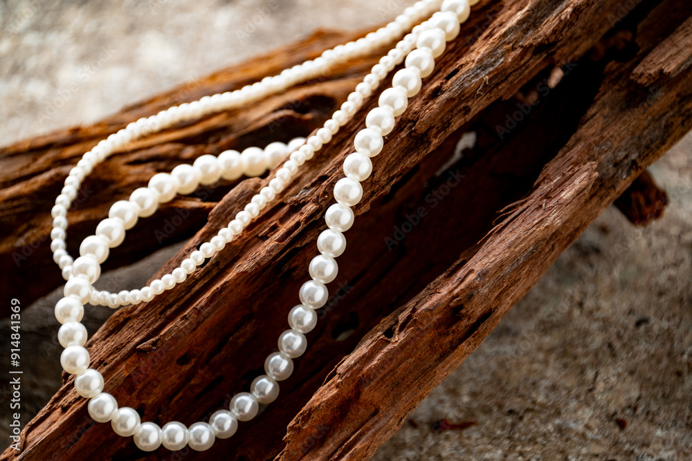 Fototapeta premium Pearl necklace on driftwood. Stylish still life image. 