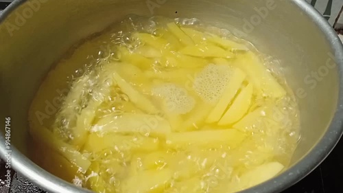 Close-up view of boiling water with yellow raw potatoes in a saucepan. Young potato are boiled in boiling water