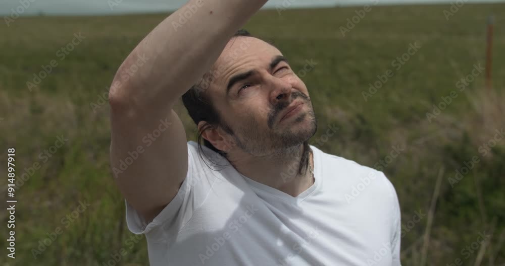 Man in white shirt raising his hand reaching for the sky. The surroundings are calm, with a cloudy sky, creating a tranquil atmosphere. The scene captures a moment of religious contemplation, praying. Man in white shirt raising his hand reaching for the sky. The surroundings are calm, with a cloudy sky, creating a tranquil atmosphere. The scene captures a moment of religious contemplation, praying.