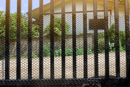 Attaching a plastic honeycomb netting to the front gate to prevent dogs, cats, and small animals from entering the house.