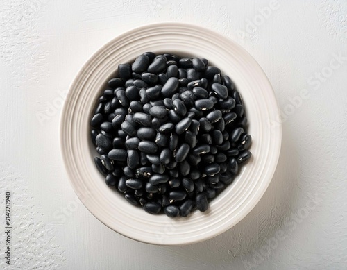 Black beans in white ceranic bowl on white background top view photo