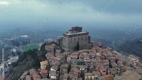 A Majestic Castle Perched Above a Historic Italian Village on a Cloudy Day photo