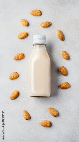 Almond Milk Simplicity: A Bottle of Plant-Based Milk with Scattered Almonds on a Minimalist Grey Background, Highlighting the Health Benefits of Vegan Nutrition. photo