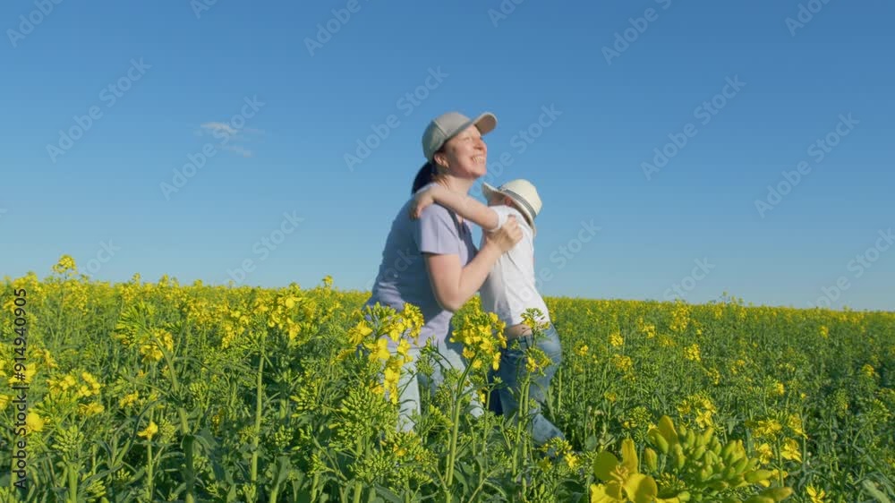 Mother And Son Playing In Field. Farmer And Little Boy Are Playing In Yellow Field Of Canola. Concept Of Organic Farming. Mother And Son Playing In Field. Farmer And Little Boy Are Playing In Yellow Field Of Canola. Concept Of Organic Farming.