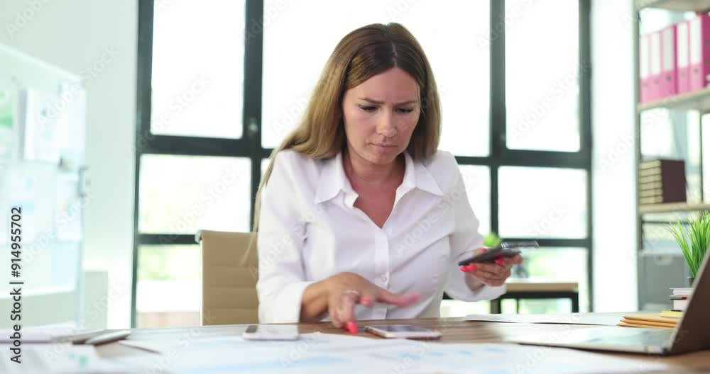 Busy female company worker examines papers taking phones to answer unknown call at workplace. Overwhelmed woman tries to cope with work tasks Busy female company worker examines papers taking phones to answer unknown call at workplace. Overwhelmed woman tries to cope with work tasks