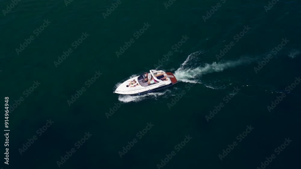 Flying over a white yacht in motion. White big boat movement on dark blue water aerial view. High-speed motor boat with people moving on the water.