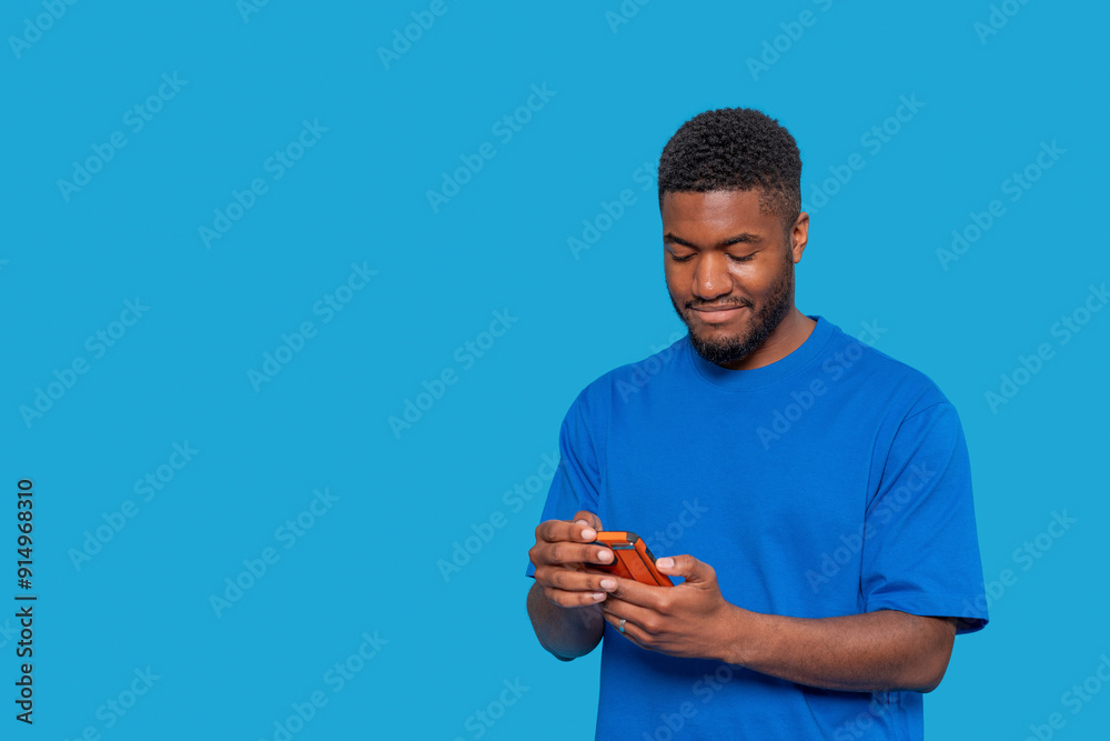 Smiling Man in Blue Shirt Using Smartphone Against Solid Blue Background