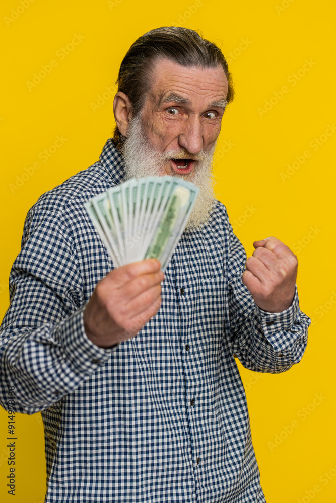 Rich happy senior old man waving money dollar cash banknotes bills like a fan, success business career, lottery winner, big income wealth pension. Mature grandfather pensioner on yellow background Rich happy senior old man waving money dollar cash banknotes bills like a fan, success business career, lottery winner, big income wealth pension. Mature grandfather pensioner on yellow background