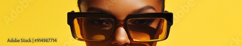 Confident Style Statement: A Close-Up of a Woman in Oversized Amber Sunglasses on a Vivid Yellow Background, Exuding a Bold Fashion Statement for E-commerce Fashion Promotion. photo