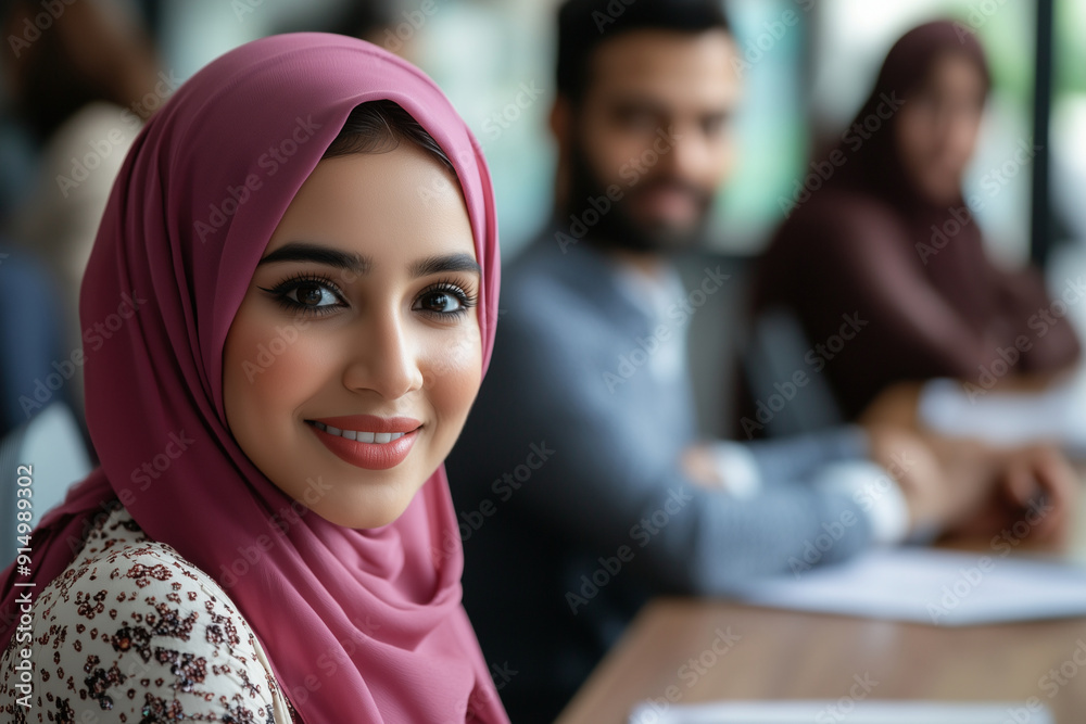 woman with a pink hijab smiling at the camera. She is surrounded by other people, but the focus is on her. Scene is happy and friendly, as the woman is enjoying herself and the company of others woman with a pink hijab smiling at the camera. She is surrounded by other people, but the focus is on her. Scene is happy and friendly, as the woman is enjoying herself and the company of others