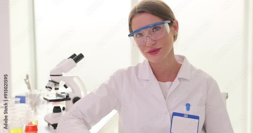 Female lab worker sits with papers showing attention to details. Woman scientist in protective glasses uses documents to ensure information accurate