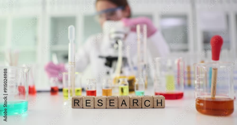 Cubes with word RESEARCH against scientist using microscope. Female researcher analyzes intricate details of sample in modern laboratory Cubes with word RESEARCH against scientist using microscope. Female researcher analyzes intricate details of sample in modern laboratory