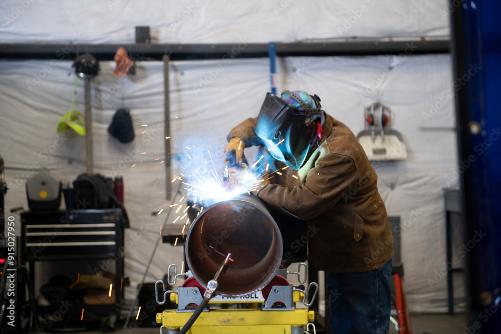 Welder working on a section of industrial pipe in his repair wor Welder working on a section of industrial pipe in his repair wor