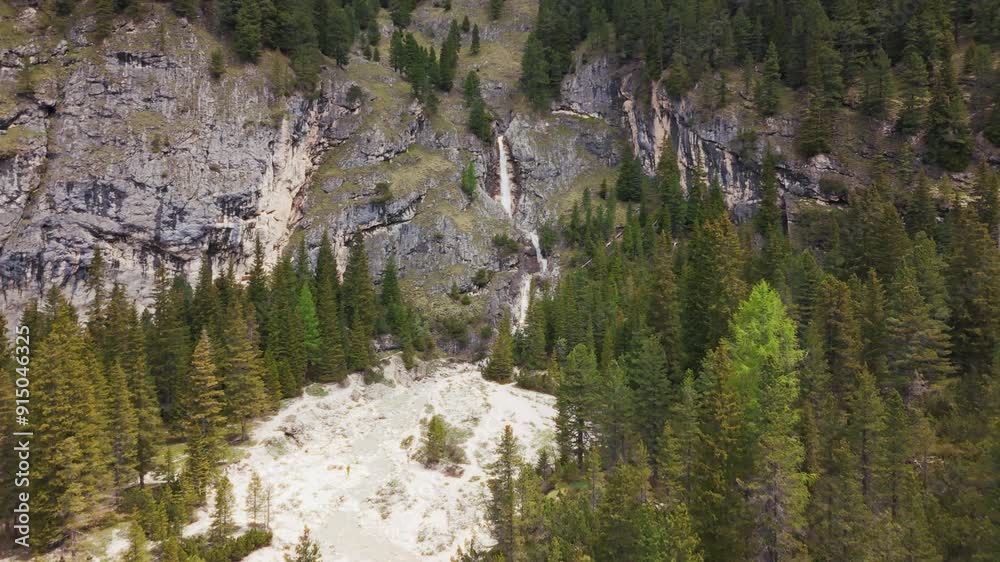 A majestic waterfall flowing through a dense alpine forest, showcasing the natural beauty of the Dolomites. A majestic waterfall flowing through a dense alpine forest, showcasing the natural beauty of the Dolomites.