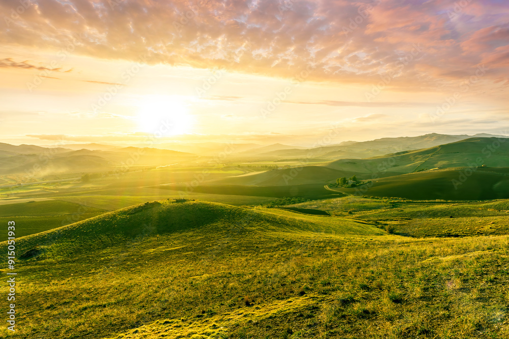 Fototapeta premium spring green field landscape in beautiful countryside with green and yellow grass, rural hills and amazing cloudy sky on background. Agriculture landscape with rural view