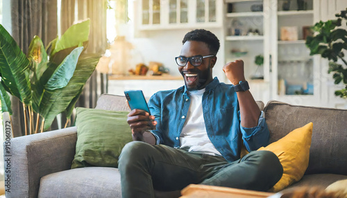Excited looking young man holding smartphone device. Man making yes gesture with clenched fist. Man with happy and satisfied expression looking at smartphone screen.