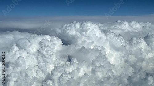 POV huge storm clouds in a blue sky seen from above. Shot from an airplane cockpit at cruise level FL300. 4K 60FPS photo