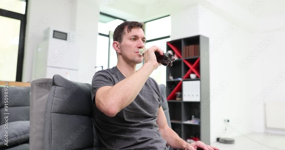 Tired thirsty man takes deep gulp from bottle with dark beverage. Clearly fatigued male worker tries to refresh among long hours at work in office Tired thirsty man takes deep gulp from bottle with dark beverage. Clearly fatigued male worker tries to refresh among long hours at work in office