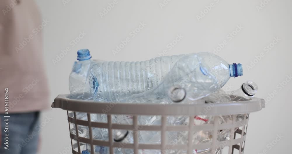 Woman throws empty water bottle into full garbage bin slow motion. Reusable plastic items collecting to reduce dangerous nature pollutions