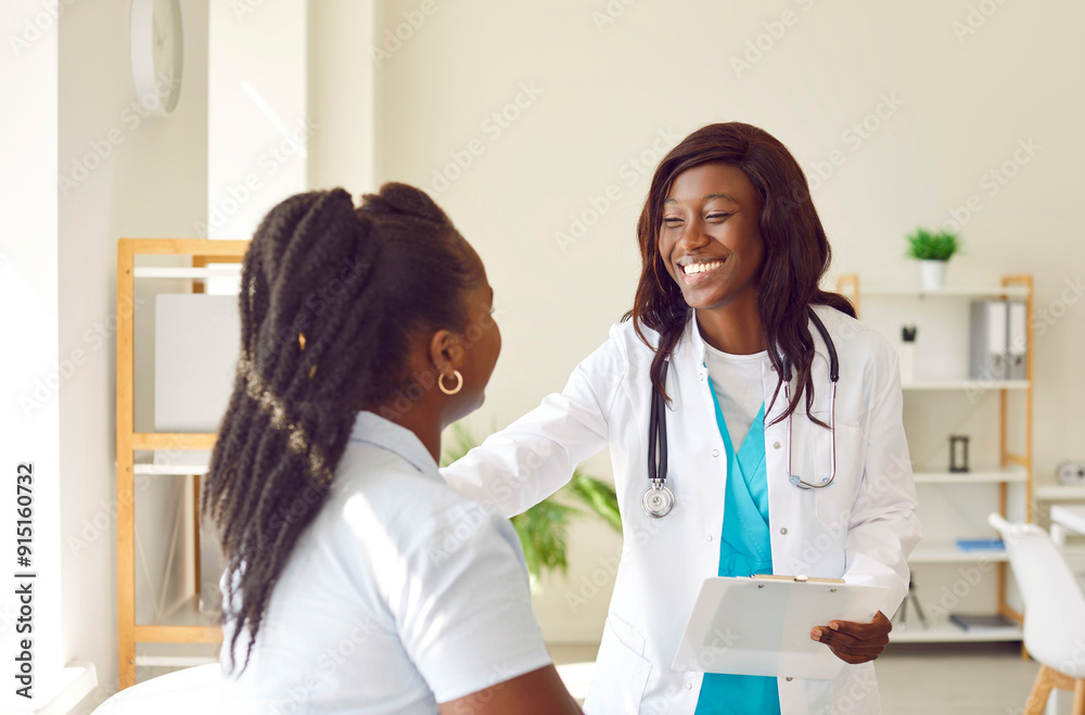 Fototapeta premium Portrait of smiling friendly female african american doctor therapist talking with a young woman patient holding report file with appointment standing in office. Medicine and health care concept.