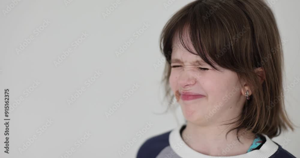 Teenager girl wrinkles face in displeasure on gray background. Child brows furrowing with nose scrunching up encountering bitter taste