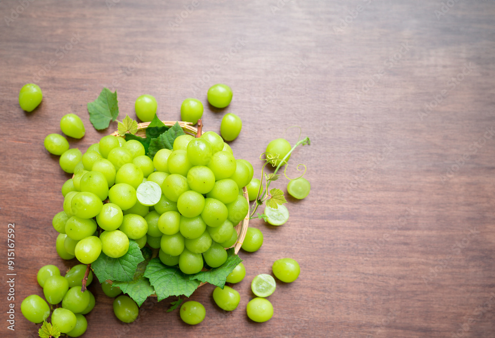 Fresh Green grape in Bamboo basket on wooden table in garden, Shine Muscat Grape with leaves with blank space in wooden background.