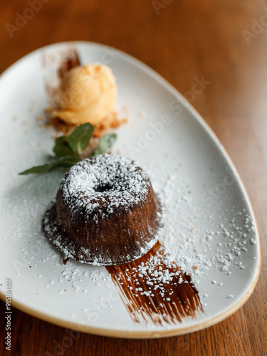 delicious dessert with creamy frosting, chocolate, fresh nuts, and fragrant herbs on a beautiful white plate in a cozy nice restaurant