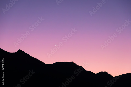 Photography silhouette of mountains in colorful sunset and moon in the sky