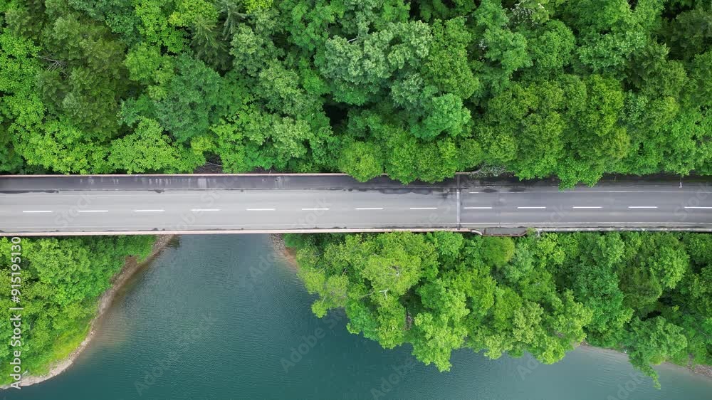 Hokkaido, Japan: Aerial overhead drone footage of a car on the road along the Chubetsu reservoir and the Ishikari river at the foot of the Asahidake mountain in Hokkaido in summer in Japan