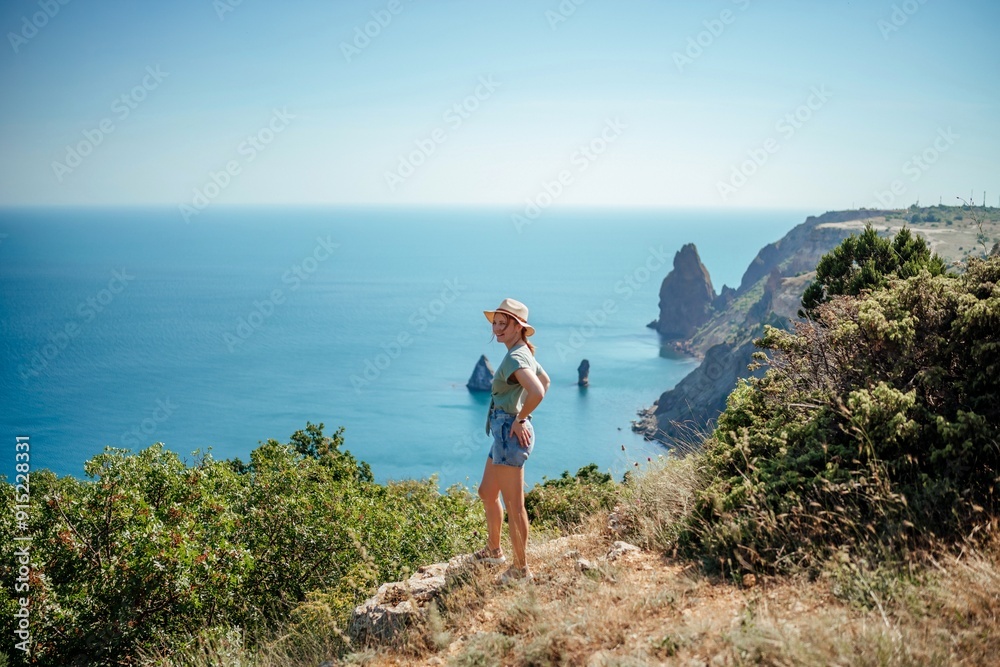 Fototapeta premium A woman stands on a hill overlooking the ocean