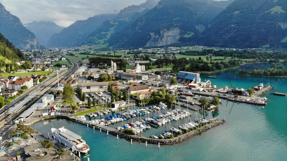 Aerial view of sunny Swiss Village Flüelen with blue water and green mountains surrounding it Aerial view of sunny Swiss Village Flüelen with blue water and green mountains surrounding it