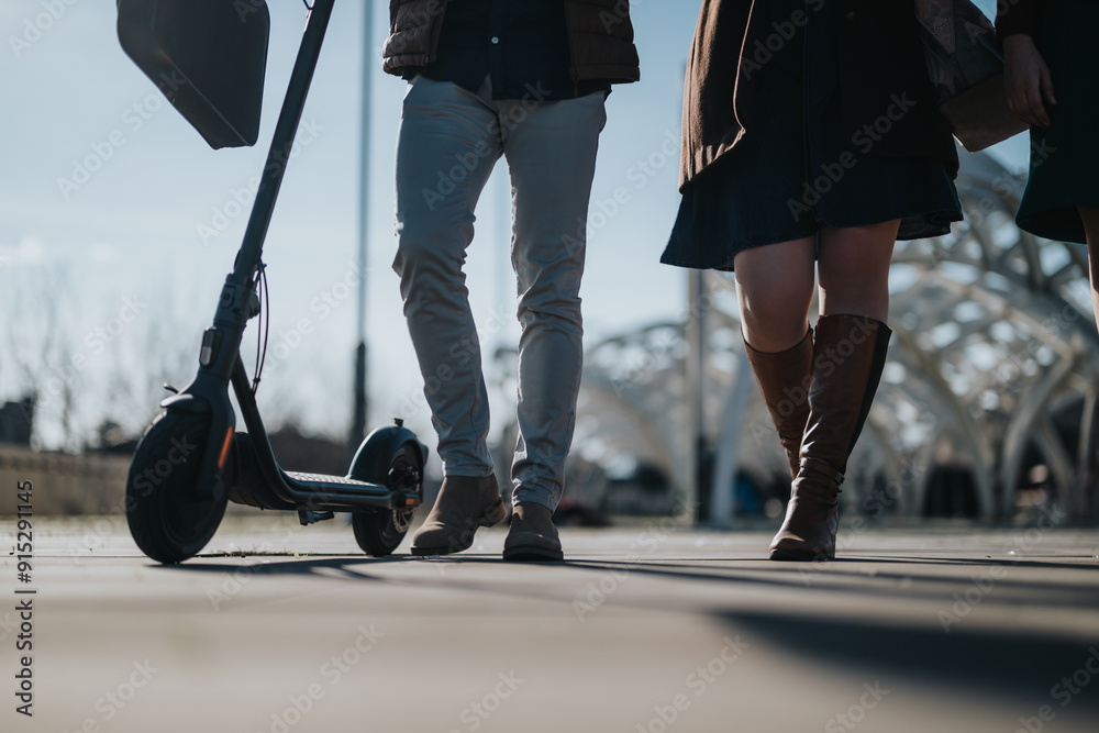 Two corporate individuals walking side by side, one with an electric scooter, in a modern city environment. Two corporate individuals walking side by side, one with an electric scooter, in a modern city environment.