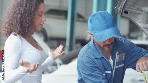 Car service concept. Auto Mechanic writing on clipboard, Auto mechanic with clipboard and woman at car shop.