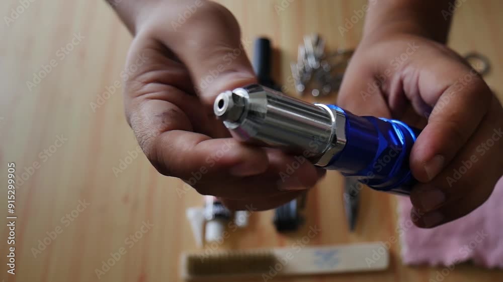 Hand holding a blue steel rivet gun adapter for drill machine Hand holding a blue steel rivet gun adapter for drill machine