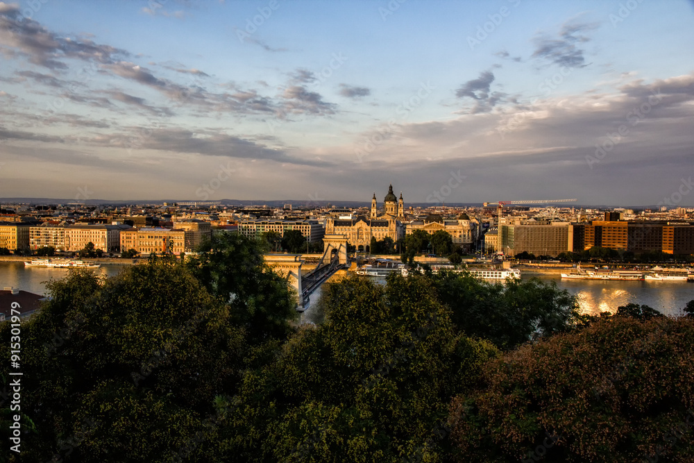 Naklejka premium Beautiful view from above of Budapest capital of Hungary in Europe. The Parliament above the Danube river flowing crossed by ships. The bridges with cars trams and bicycles. Travel concept