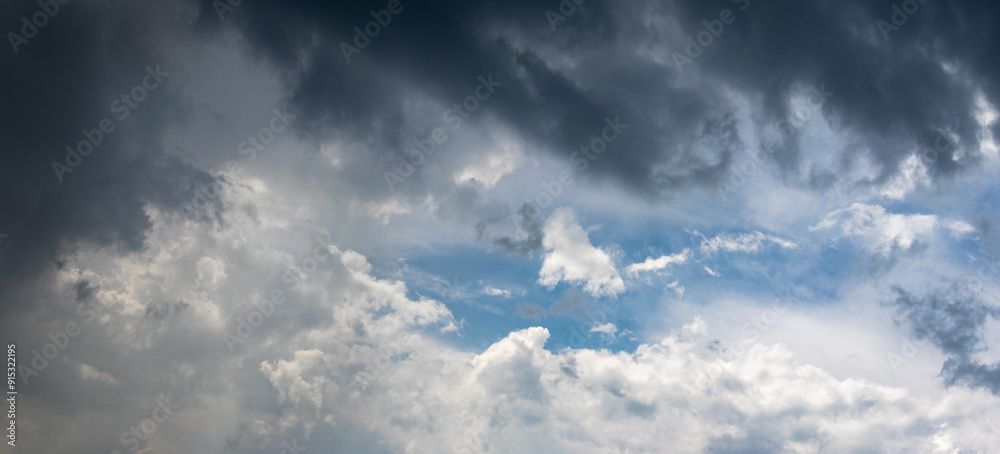 Fototapeta premium Dark storm clouds cover the blue sky with white clouds